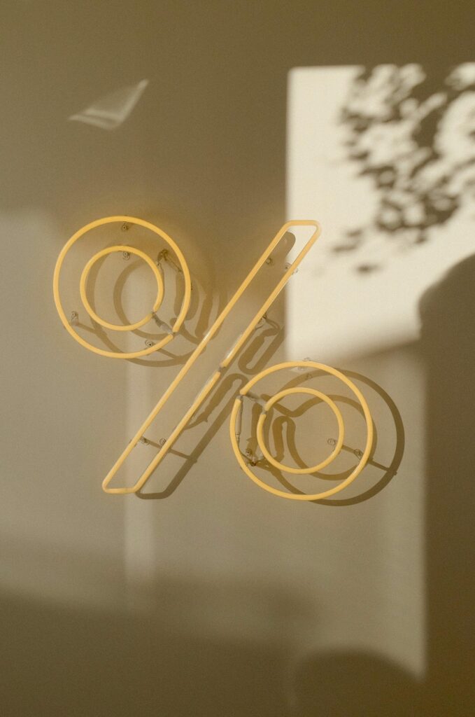 Artistic yellow neon percentage sign against abstract background, evokes modern and conceptual themes.